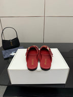 Red leather mule flats with gold buckles and logo emblem, viewed from heel side