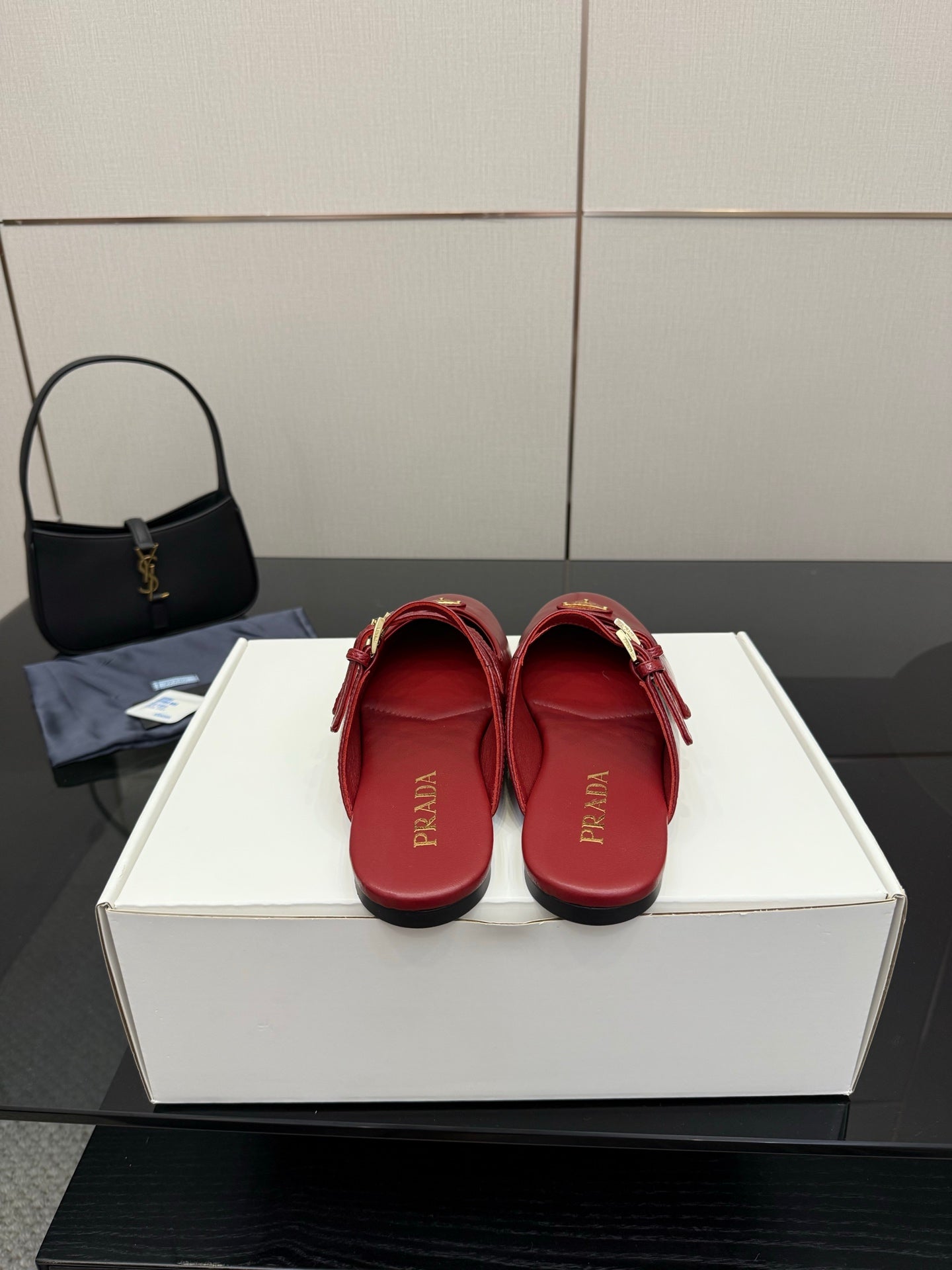 Red leather mule flats with gold buckles and logo emblem, viewed from heel side