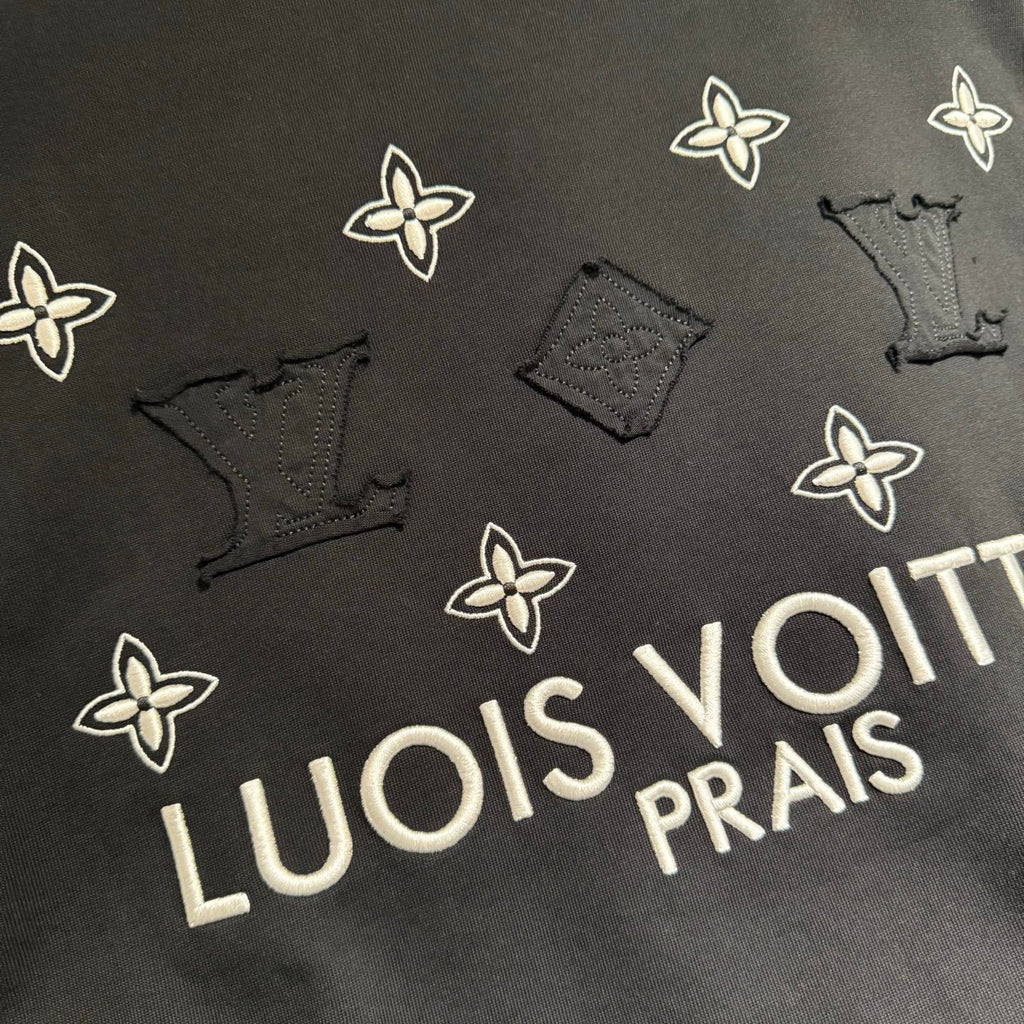 Louis Vuitton black T-shirt detail with white flower icons and partial 'LOUIS' lettering