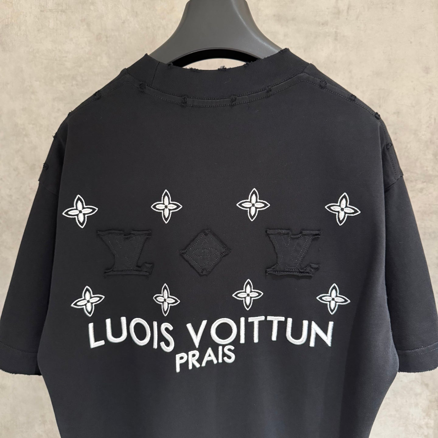 Louis Vuitton black T-shirt with white flower icons and 'LOUIS VUITTON PRAIS' on back