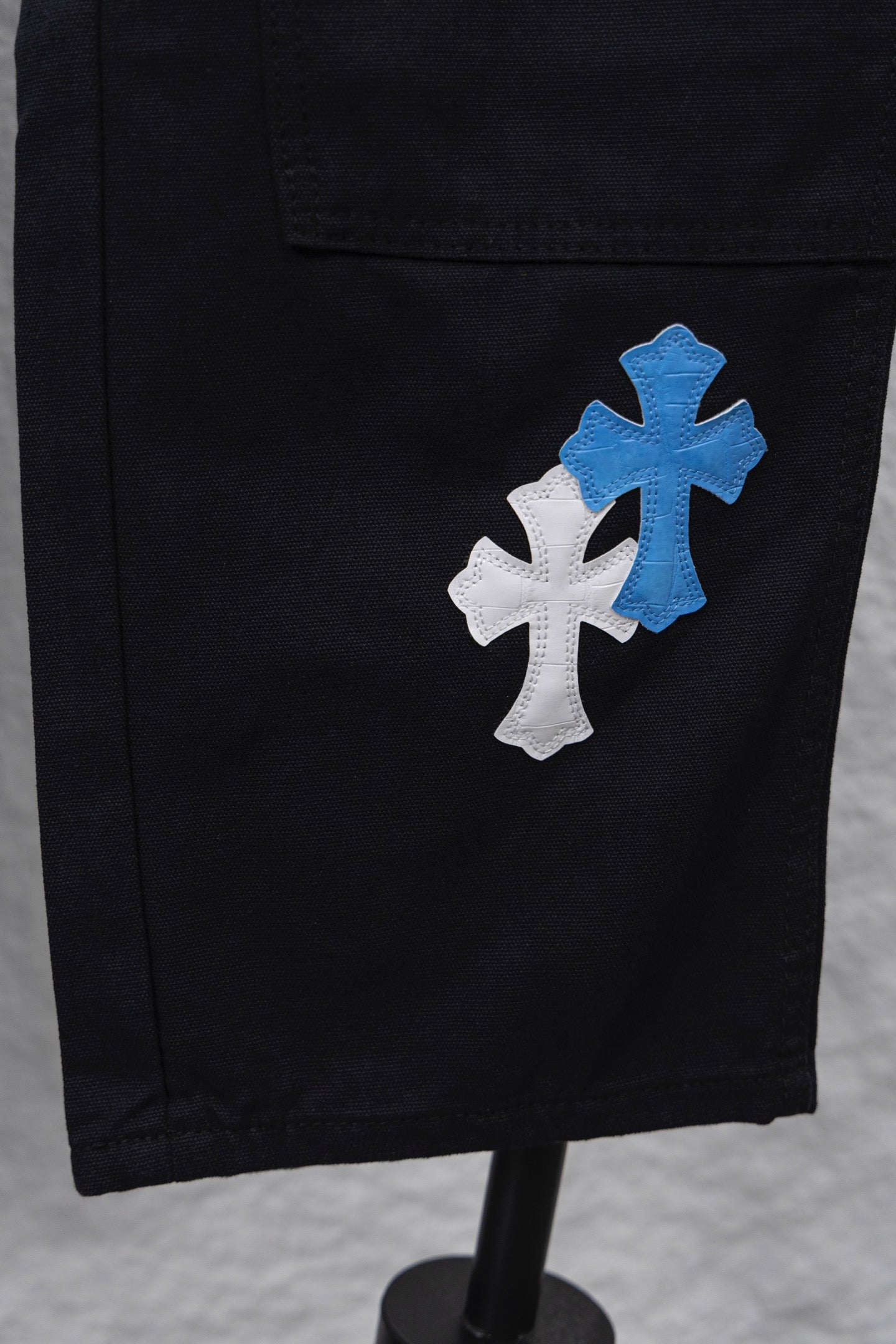 Black cargo pants with blue-and-white cross patch on the leg pocket