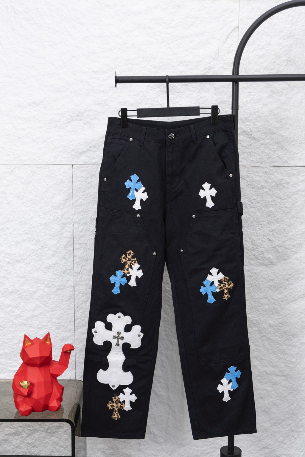 Black cargo pants with cross-style appliques in blue, white, and leopard print
