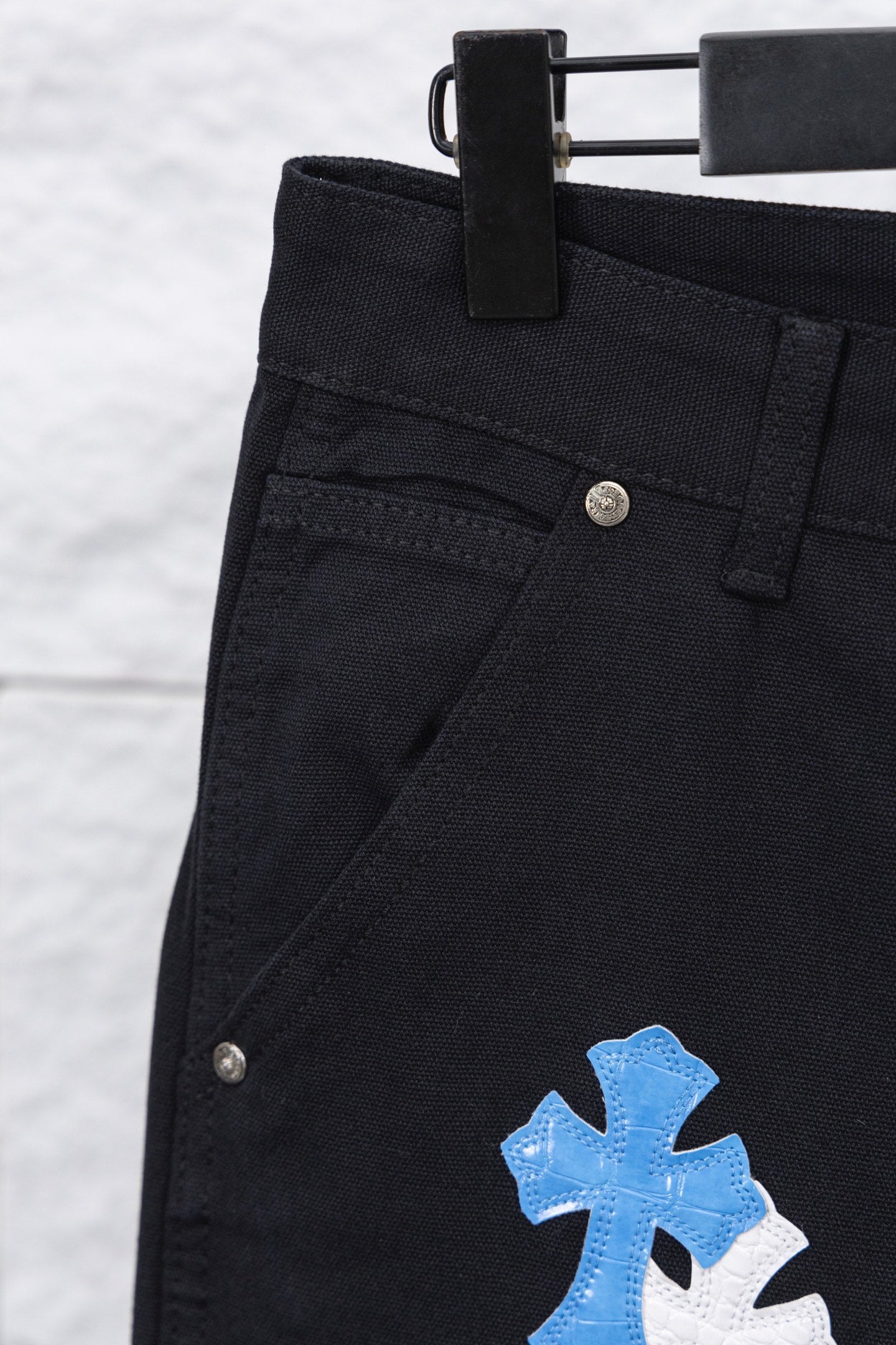 Black cargo pants with belt loop and blue cross patch near side pocket