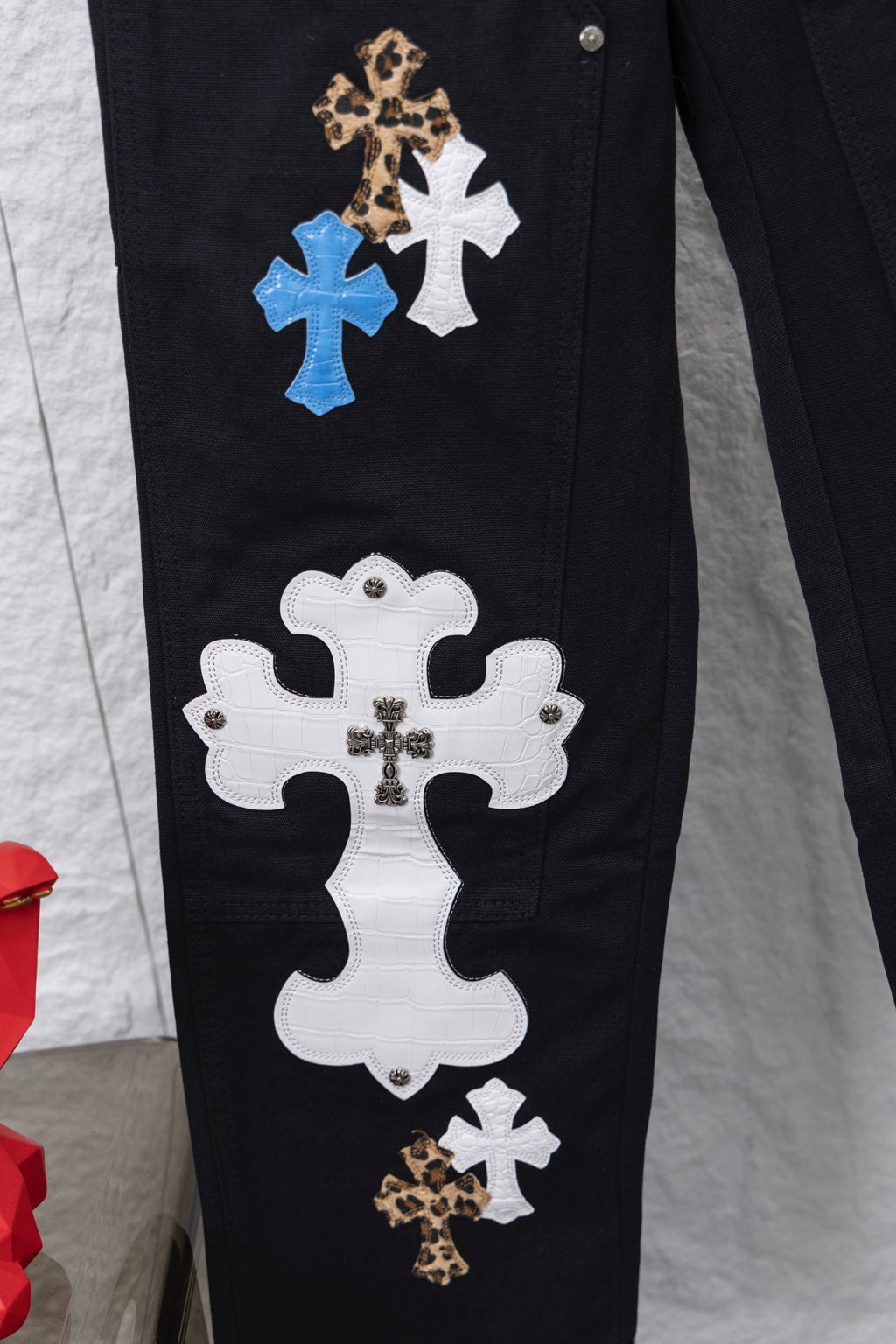 Black cargo pants with large white and blue cross patches on side seam