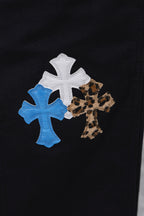 Black cargo pants with close-up cross appliques in blue, white, and leopard print