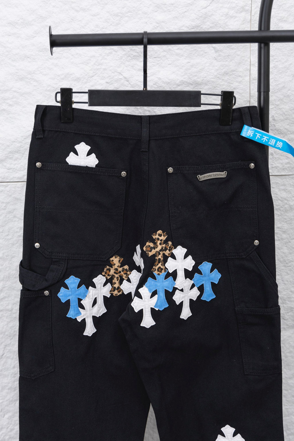 Black cargo pants with large front cross appliques in blue, white, and gold tone