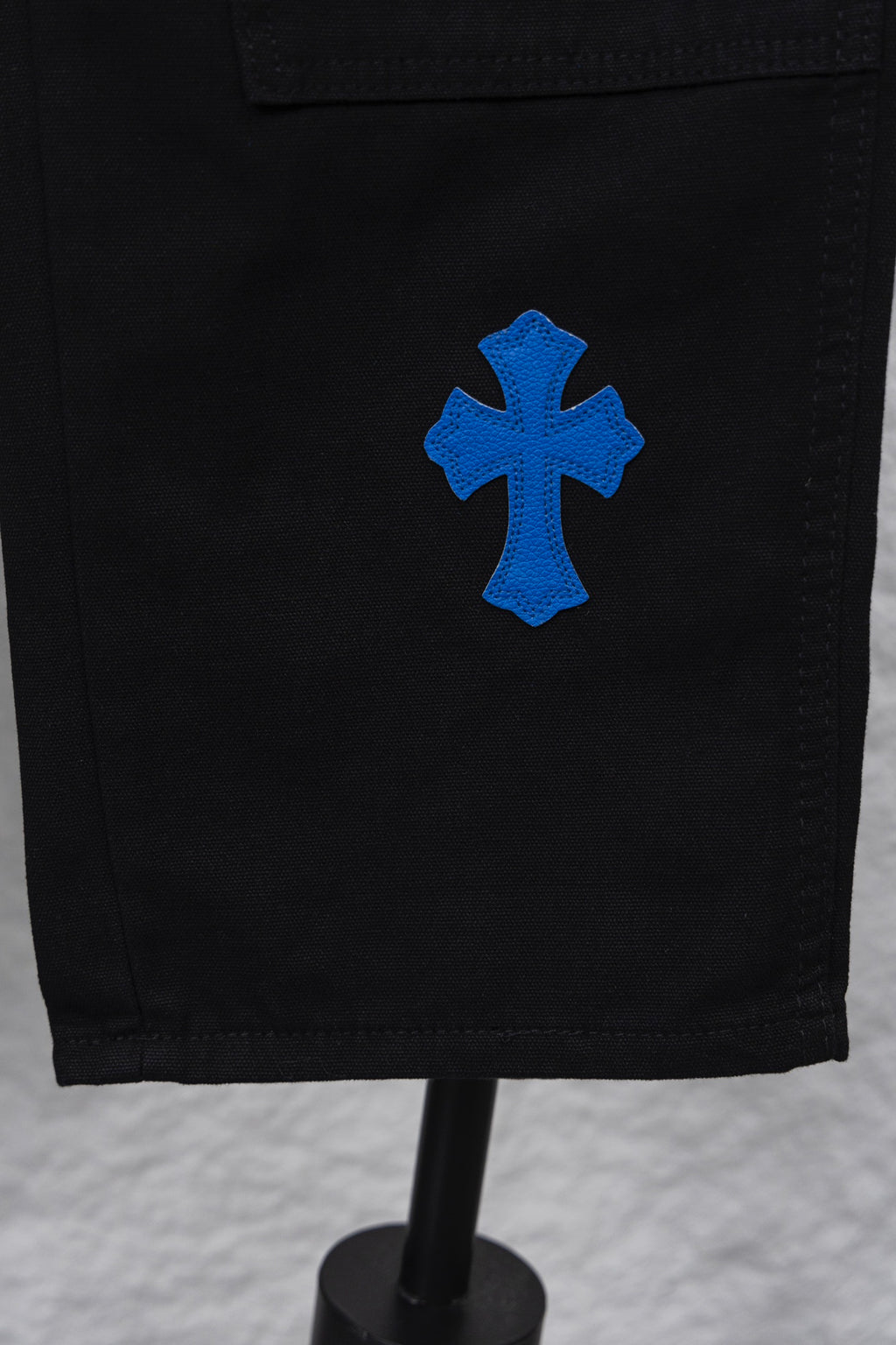 Black cargo pants with blue cross patch on side hem