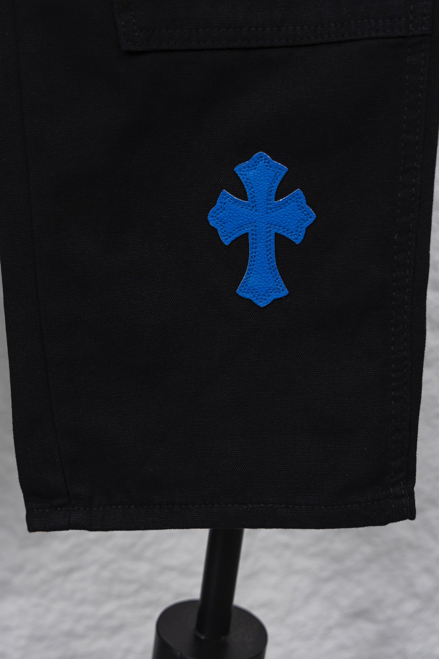 Black cargo pants with blue cross patch on side hem