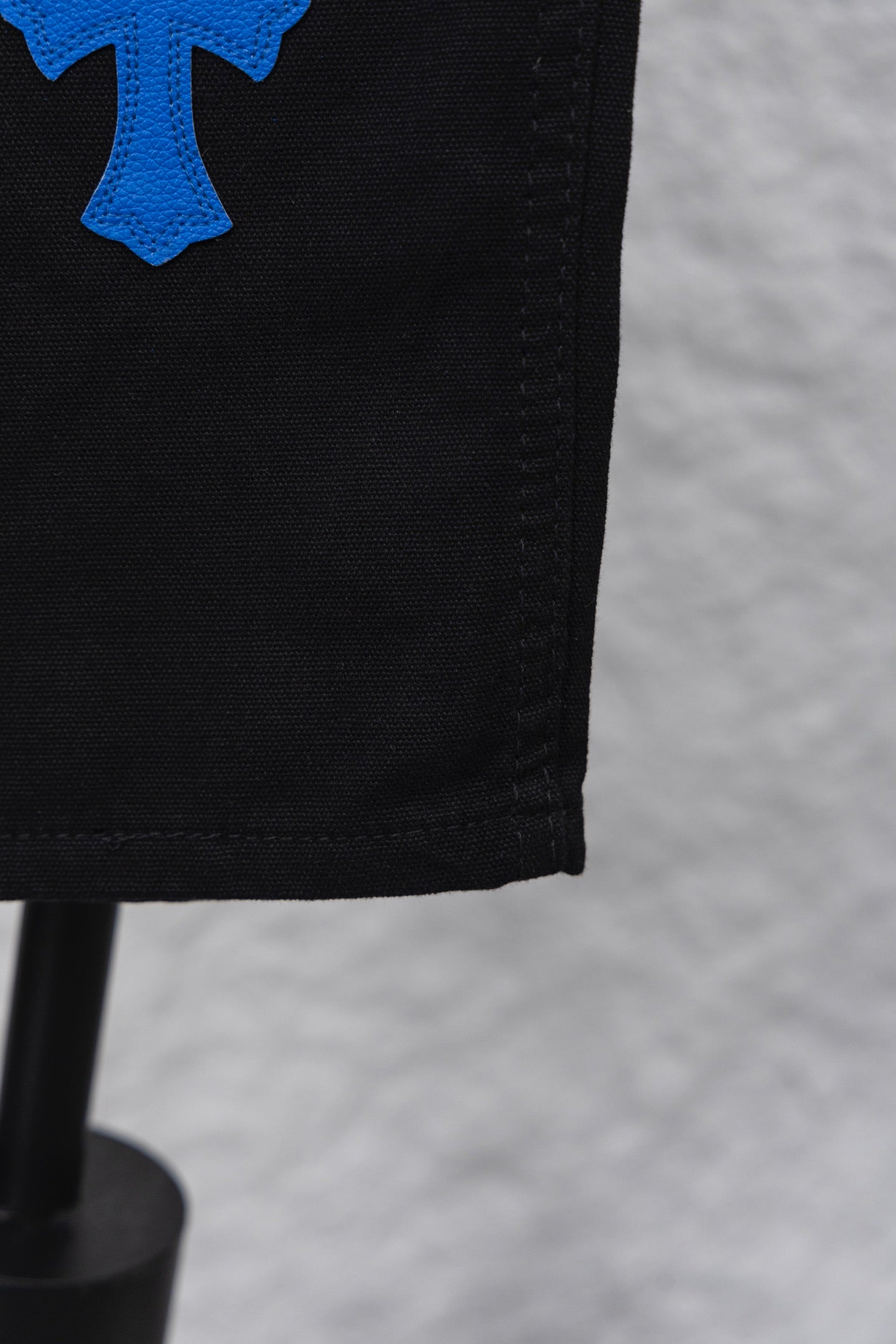 Black pants hem close-up with blue cross patch