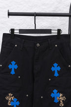 Black cargo pants front close-up with blue cross patches and decorative buttons