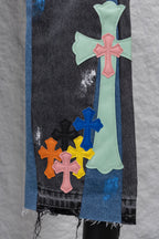 Black denim pants with large cross patches in mint, pink, blue, and orange; close-up.