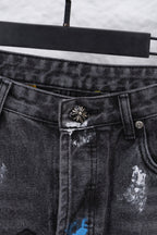 Close-up of black denim pants button and waistband with decorative metal emblem; zipper side.