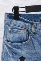 Light blue denim pants with button-front pocket details, close-up.