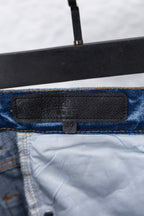 Light blue denim pants with black leather-look belt patch, close-up.