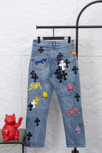 Light blue denim pants with multicolor graphic patches, front view.