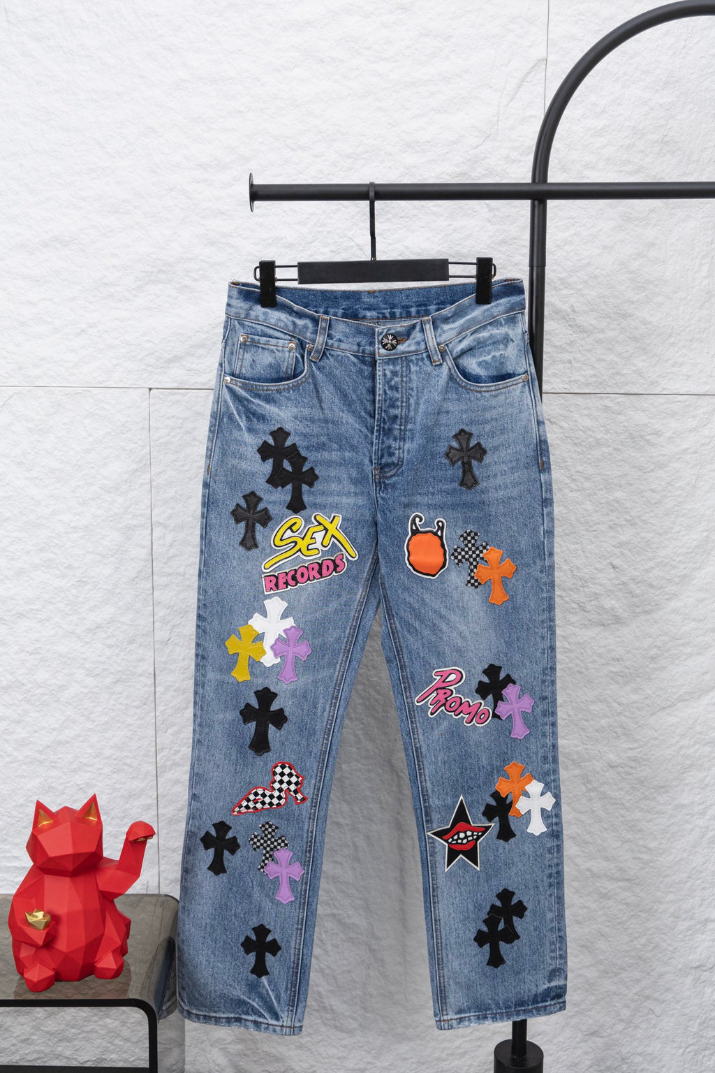 Light blue denim pants with colorful graphic patches, front view.