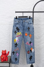 Light blue denim pants with colorful graphic patches, front view.