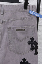 Light gray denim pants front pocket with small stitched brand patch and cross detail