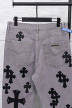 Light gray denim pants with black cross motifs on front pockets, close-up