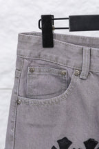 Light gray denim pants with curved front pocket and small metal buttons, close-up