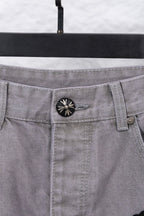 Light gray denim pants waistband with circular button and belt loops, close-up