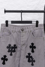 Light gray denim pants with black cross motifs across the legs, front view