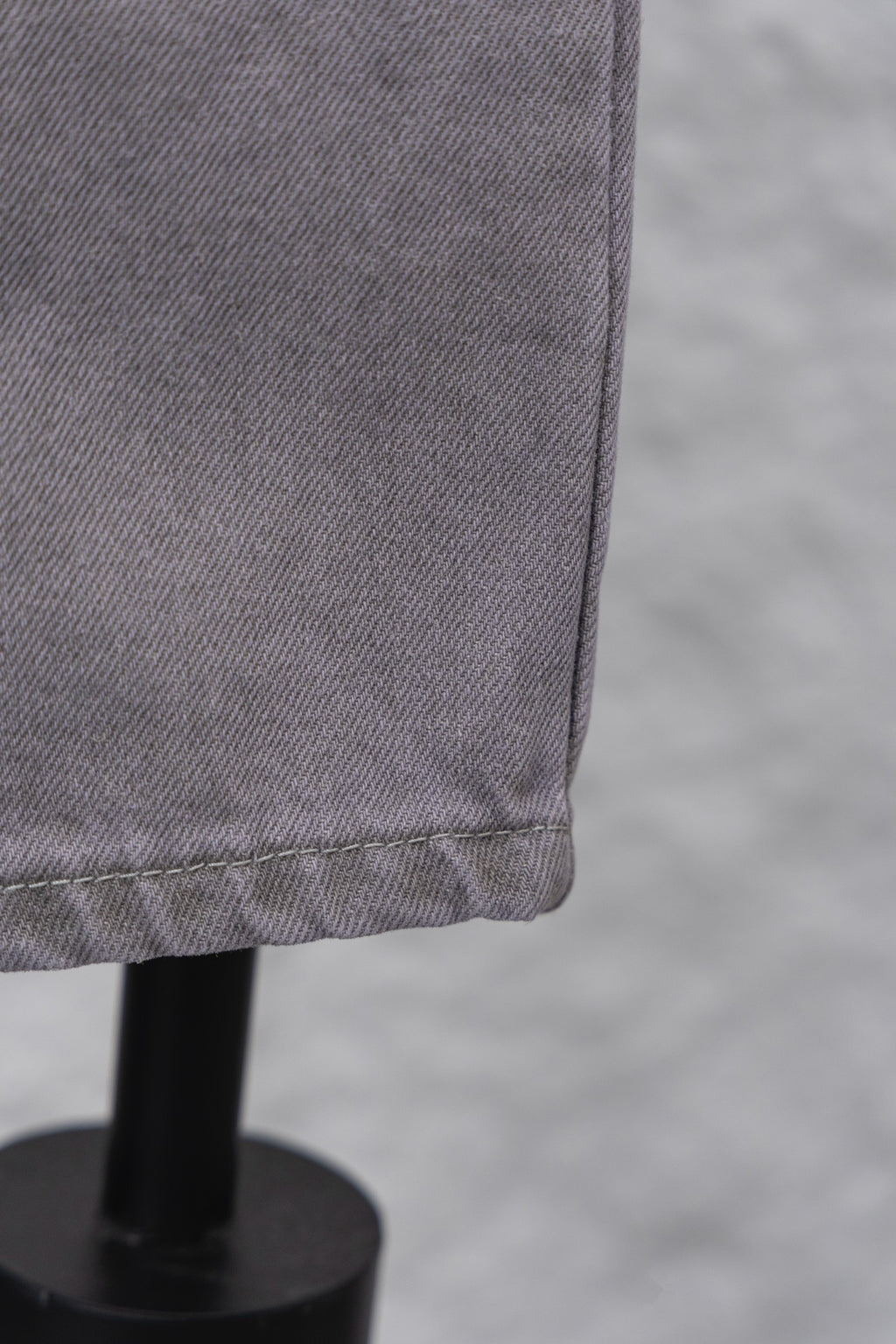 Light gray denim pant leg hem with stitched edge, close-up