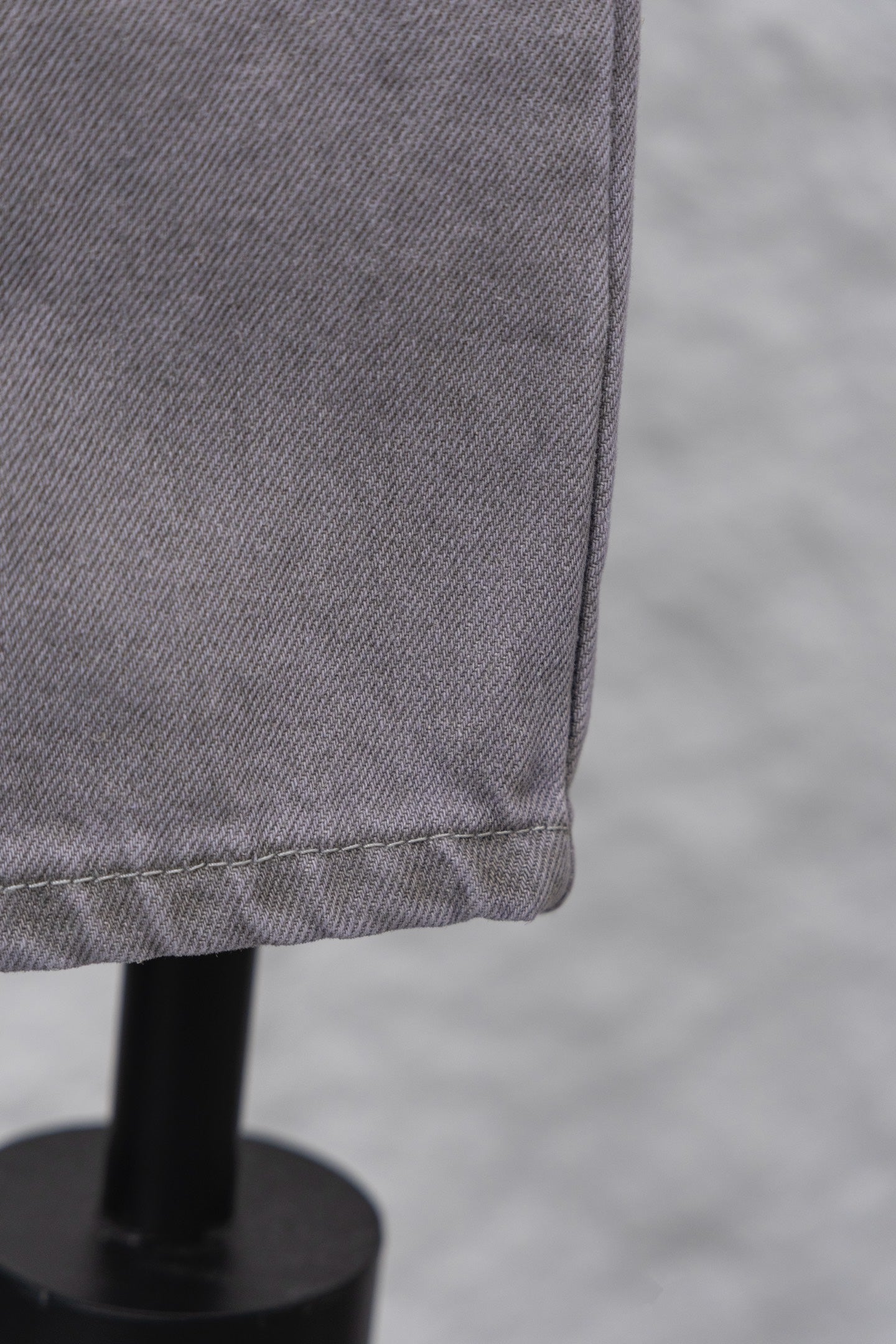 Light gray denim pant leg hem with stitched edge, close-up