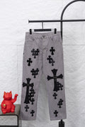 Light gray denim pants with black cross and bow-like appliques, front view