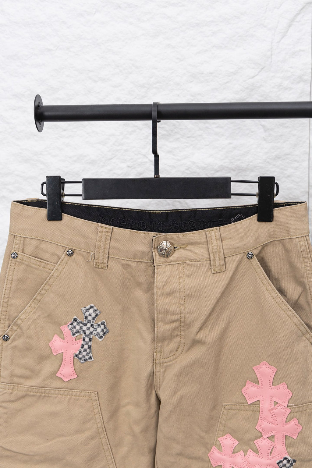 Tan pants front view with black inner waistband and pink and patterned cross patches