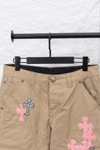 Tan pants front view with black inner waistband and pink and patterned cross patches