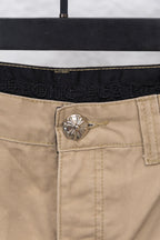 Tan pants button and waistband close-up with embossed brand detail