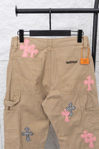 Beige cargo pants with cross appliqué patches and orange logo tag