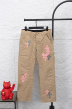Tan pants with pink and patterned cross appliques on the legs and a black waistband