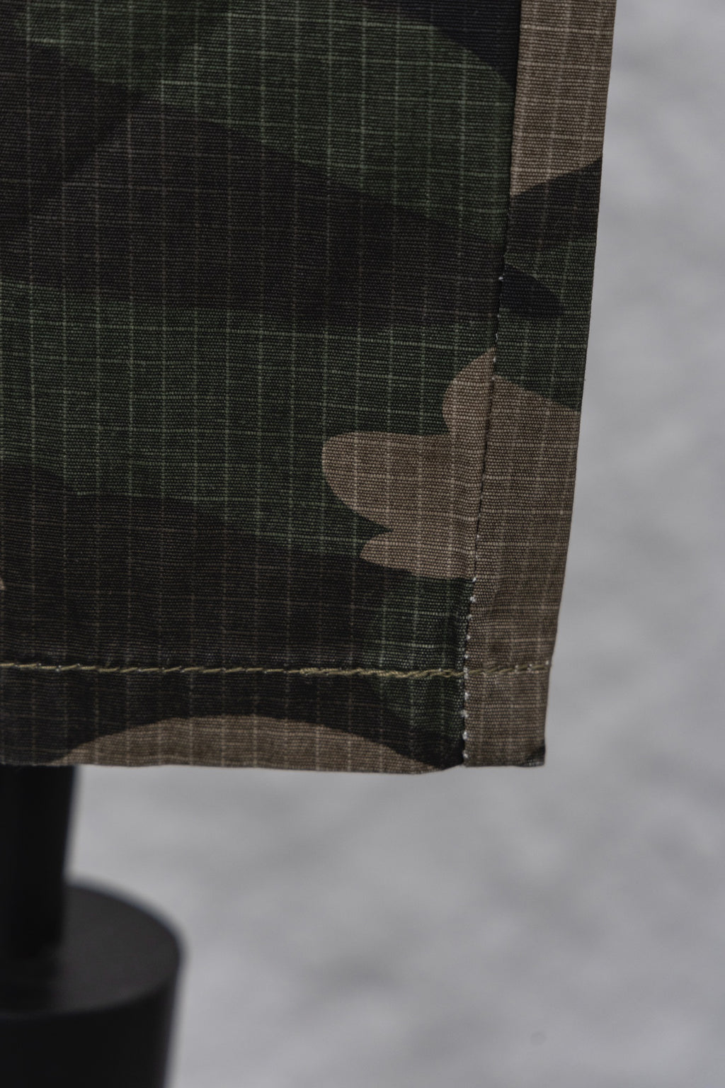 Hem and pocket edge of camouflage pants with dark stitching close-up