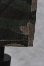 Hem and pocket edge of camouflage pants with dark stitching close-up