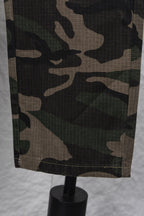 Camouflage pants fabric close-up showing green, brown, and black patterning
