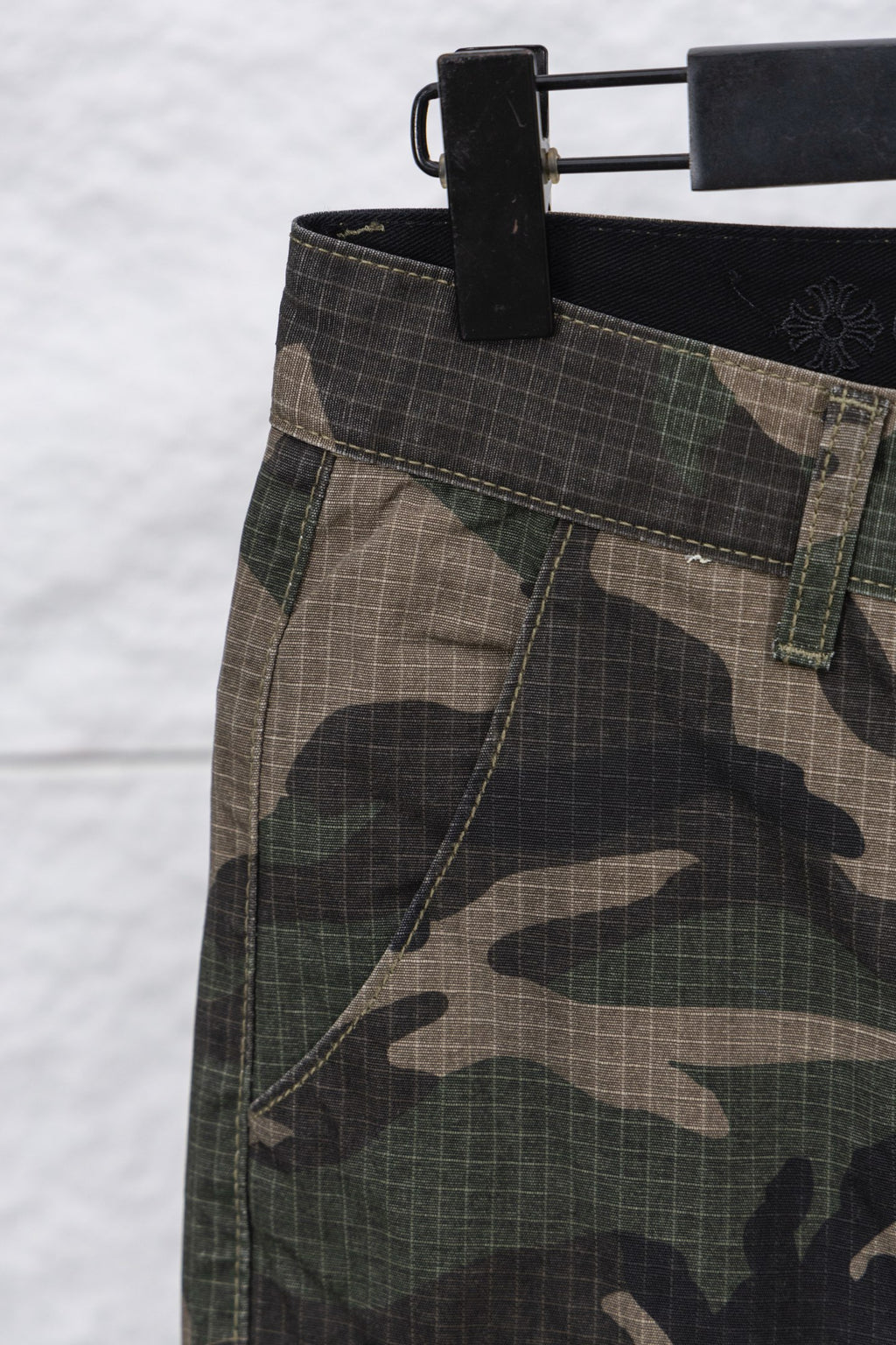 Camouflage pants fabric and waistband close-up with dark waistband and belt loops
