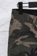 Camouflage pants fabric and waistband close-up with dark waistband and belt loops