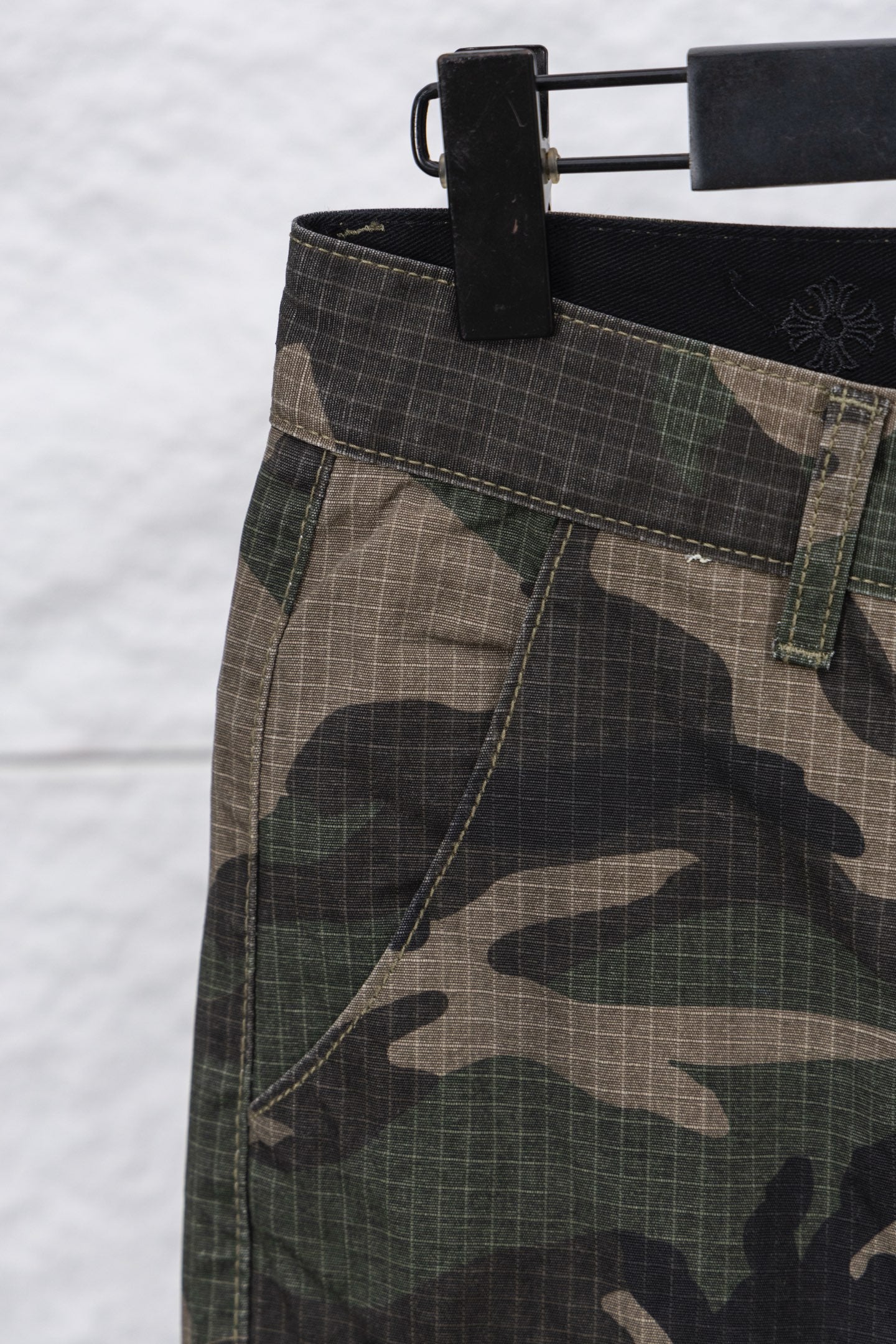 Camouflage pants fabric and waistband close-up with dark waistband and belt loops