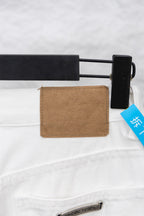 White denim pants waistband with brown patch label near belt loop