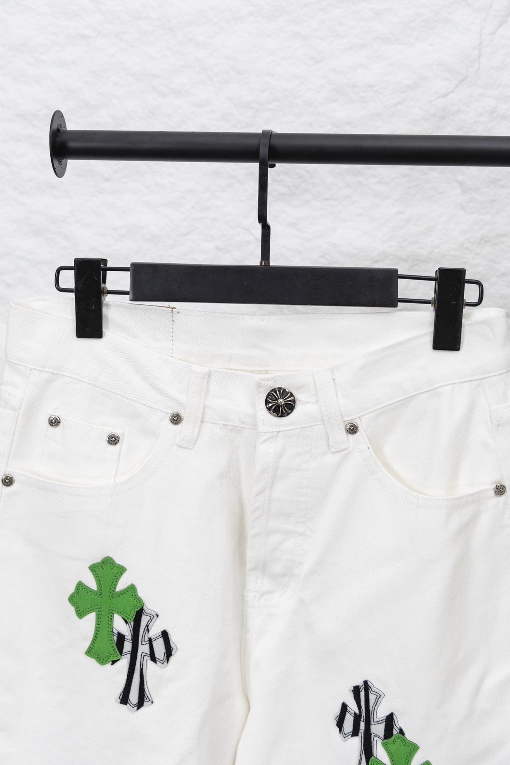 White denim pants with green and black cactus-style patches on front, close-up