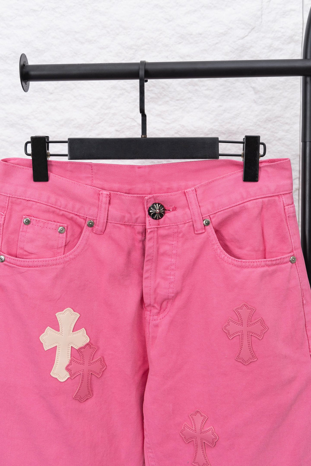 Pink denim pants with cross patches on legs and front pocket openings