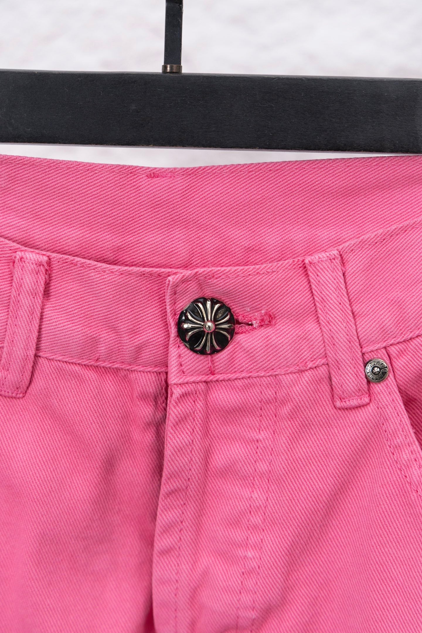 Pink denim pants with front waistband detail and round decorative button