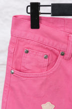 Pink denim pants back pocket area with buttoned pockets and cross applique