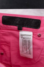 Pink denim pants with black waistband label and side button closure