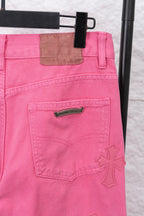 Pink denim pants with logo patch, front pocket stitching, and cross applique