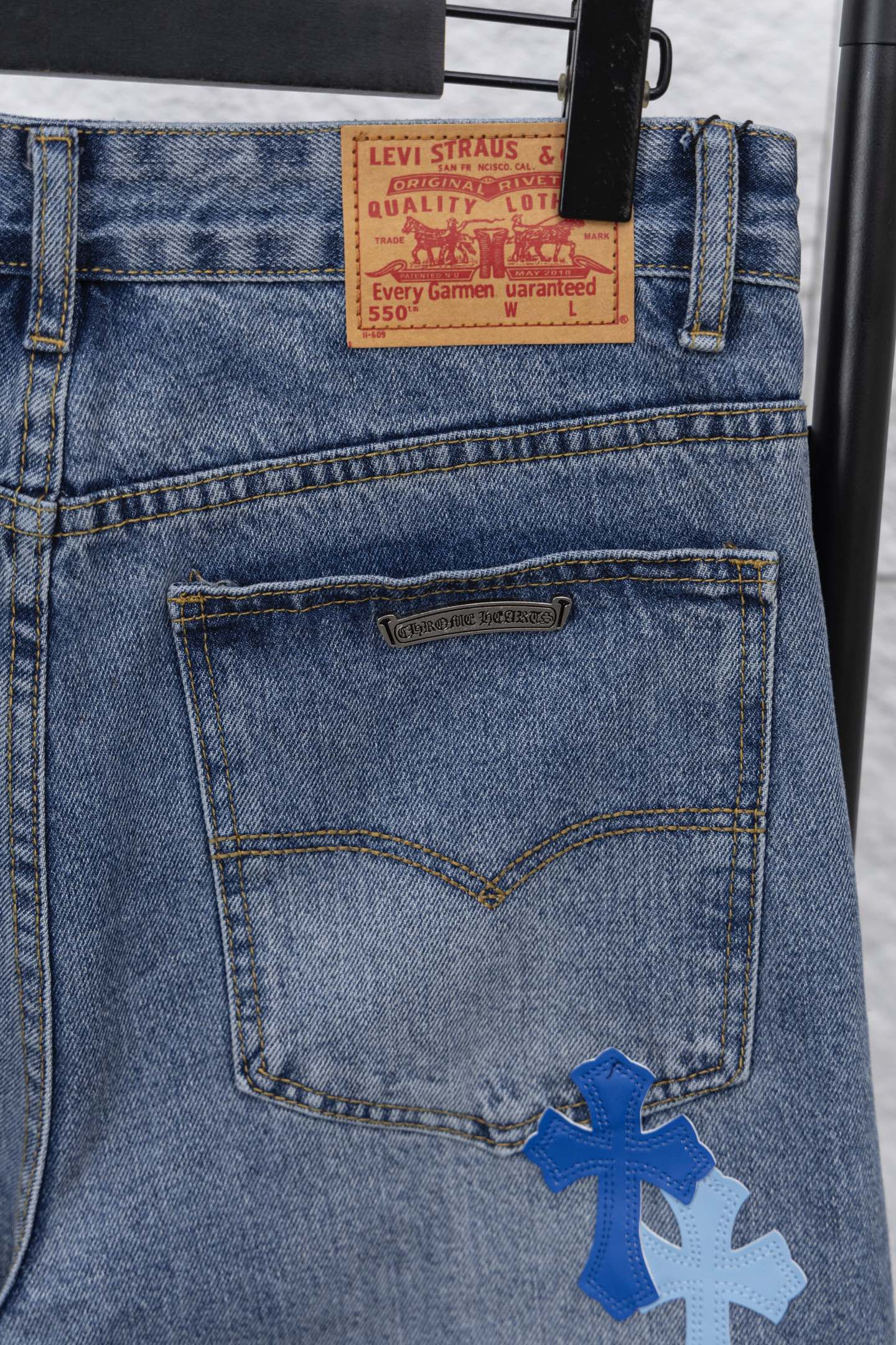 Denim pants with stitched front pocket and blue appliqué logo patch