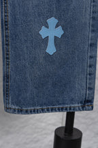 Light blue denim fabric with a blue cross patch near the hem