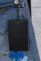 Light blue denim with a hanging black brand tag near the pocket